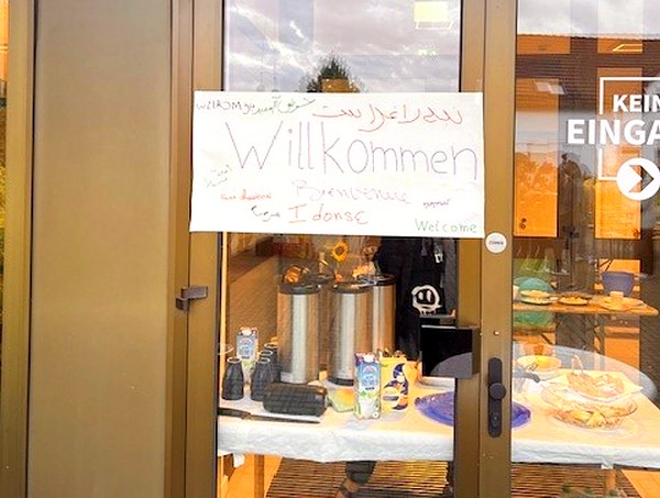 Die Bewohner und Gäste werden von einem bunten und in vielen Sprachen geschriebenen "Willkommen"-Schild begrüßt. 