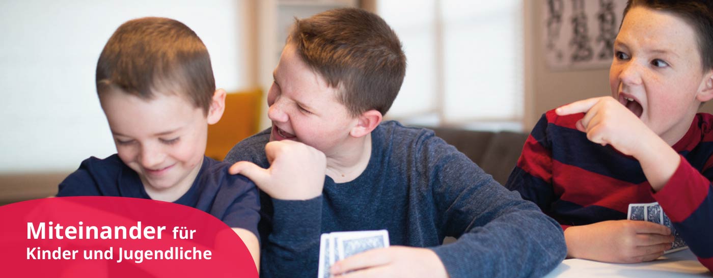 Drei Jungen spielen Karten an einem Tisch