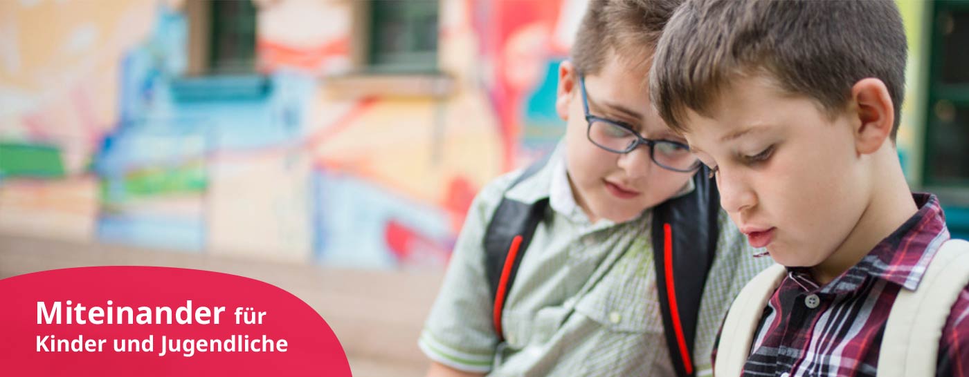 Pädagogische Fachkraft als Gruppenleitung betreut Hort Plus Kinder im Kloster Moosen, die mit einem Buch auf einer Bank im Garten sitzen