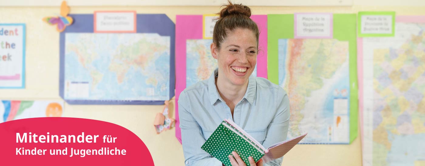 Lehrerin sitzt vor der Klasse mit einem Buch in der Hand