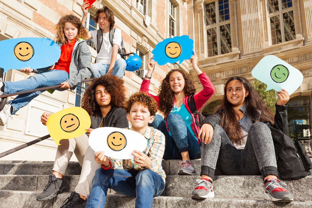 Eine Gruppe Jugendlicher hält bunte Sprechblasen aus Karton in die Höhe