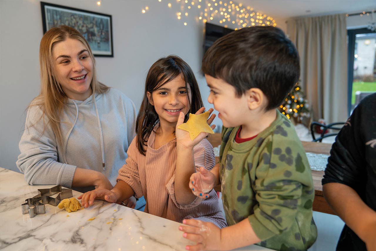 Eine Erzieherin und zwei Kinder backen Plätzchen.