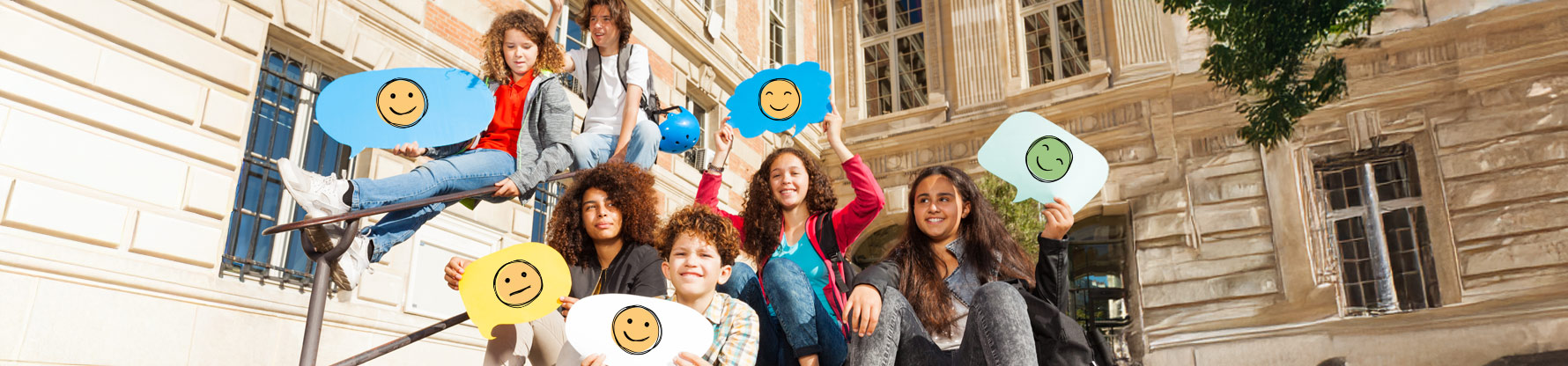 Eine Gruppe Jugendlicher hält bunte Sprechblasen aus Karton in die Höhe