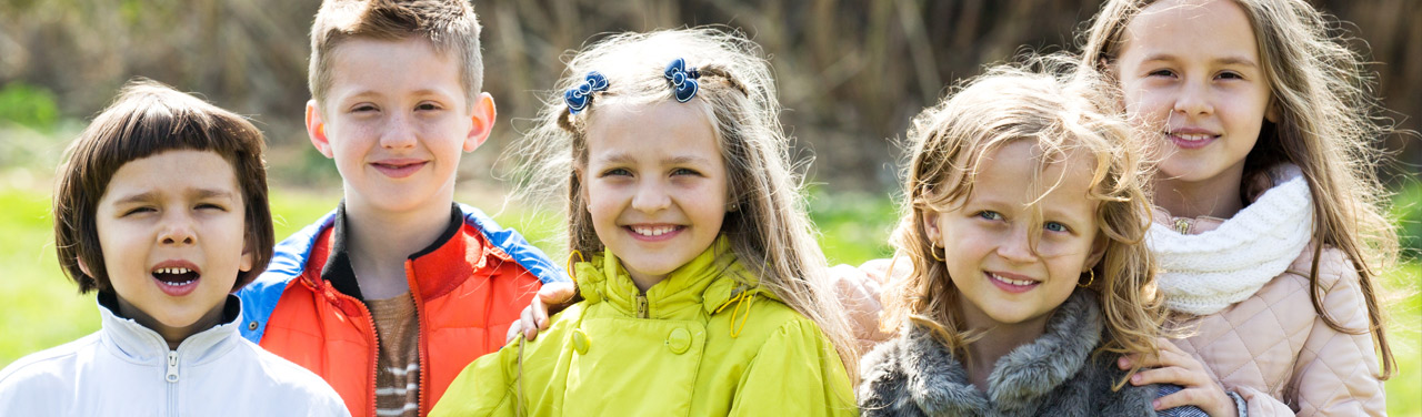 Eine Gruppe Kinder auf einer Wiese, die in die Kamera schauen.