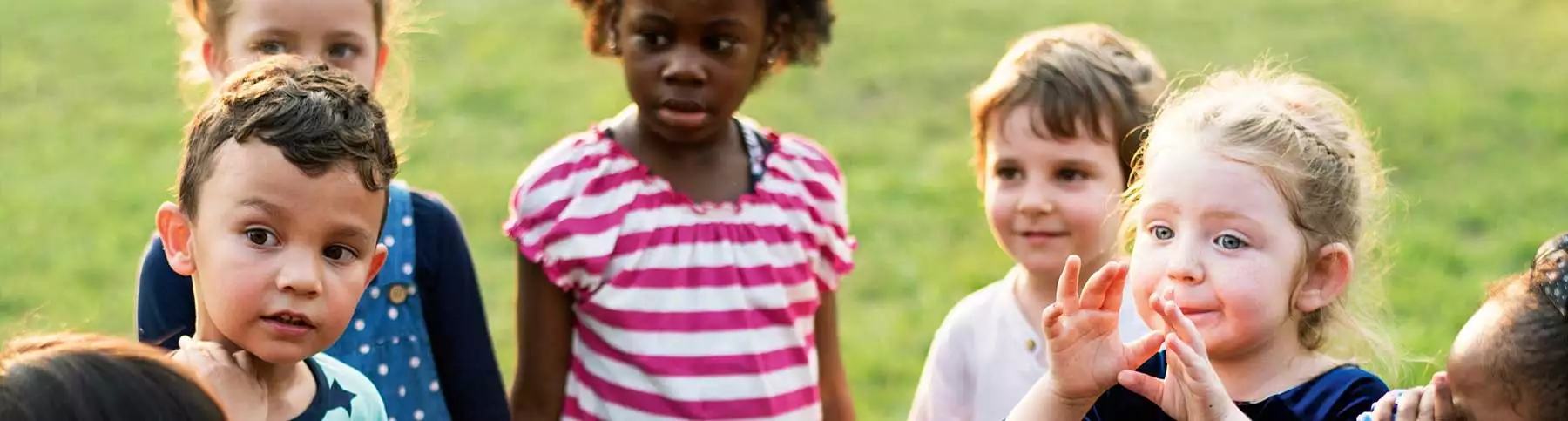 Ein Gruppe kleiner Kinder beim Spielen auf einer Wiese.