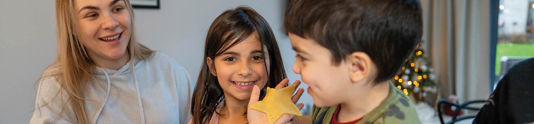 Im Vordergrund lacht ein Mädchen beim Malen, dahinter ein Junge und ein Mädchen mit der Psychologin beim Malen.