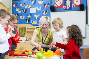 Erweitertes Betreuungsangebot: Erzieherin spielt mit Kindergartenkindern